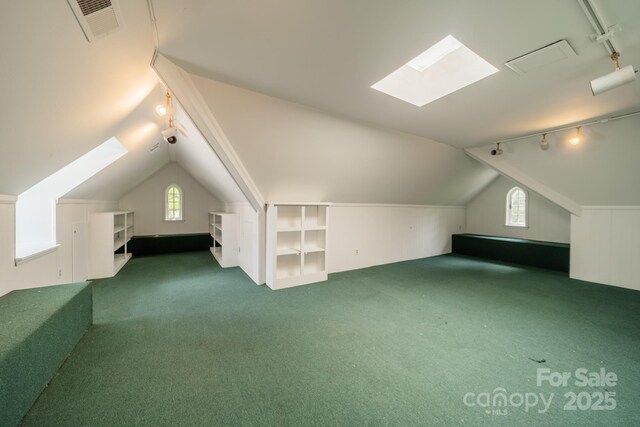 additional living space with carpet floors, vaulted ceiling with skylight, and visible vents