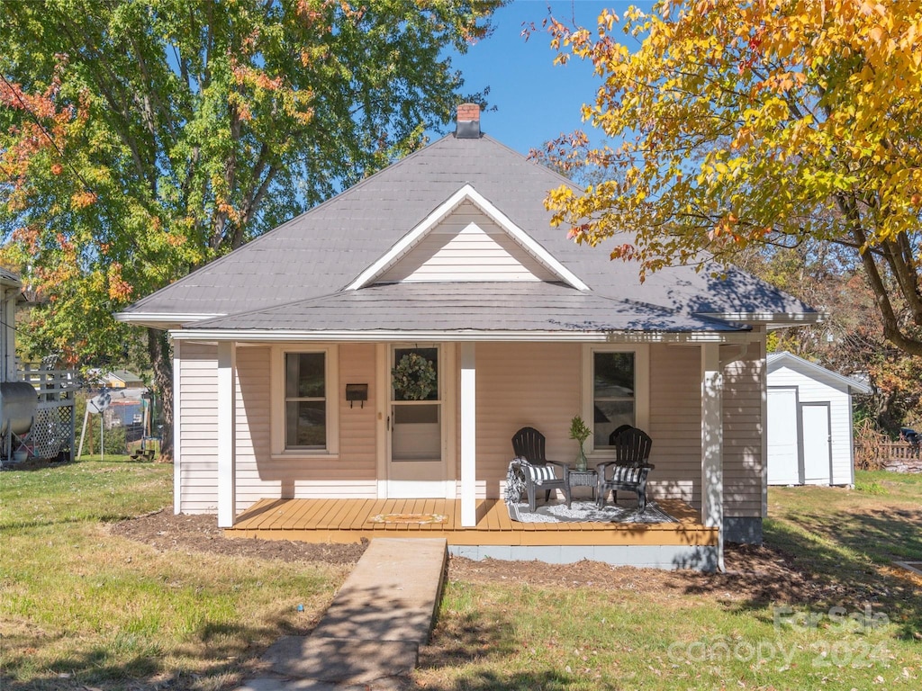 bungalow-style house with a wooden deck, a front yard, an outbuilding, and a garage