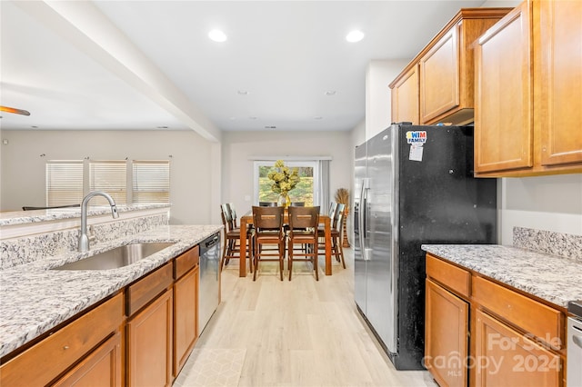 kitchen featuring sink, appliances with stainless steel finishes, light wood-type flooring, and light stone counters