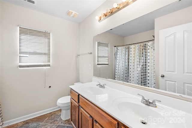 bathroom with curtained shower, vanity, a healthy amount of sunlight, and toilet