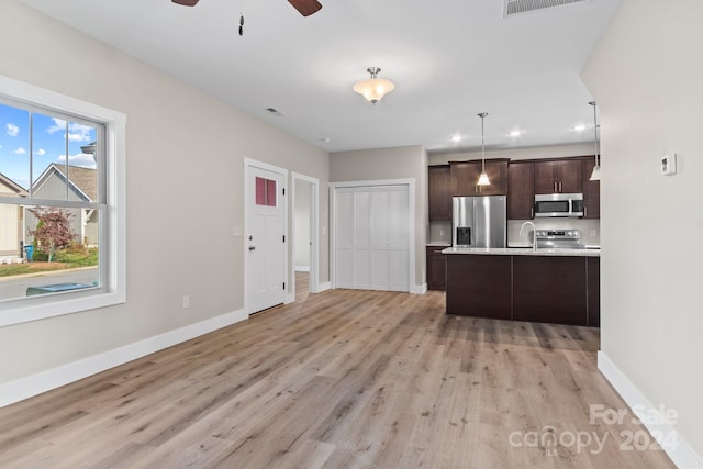 kitchen featuring stainless steel appliances, ceiling fan, light wood-type flooring, dark brown cabinets, and pendant lighting