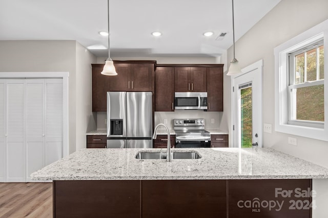 kitchen with dark brown cabinetry, stainless steel appliances, sink, and decorative light fixtures