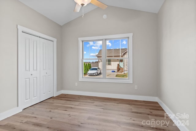 unfurnished bedroom featuring light hardwood / wood-style flooring, lofted ceiling, ceiling fan, and a closet