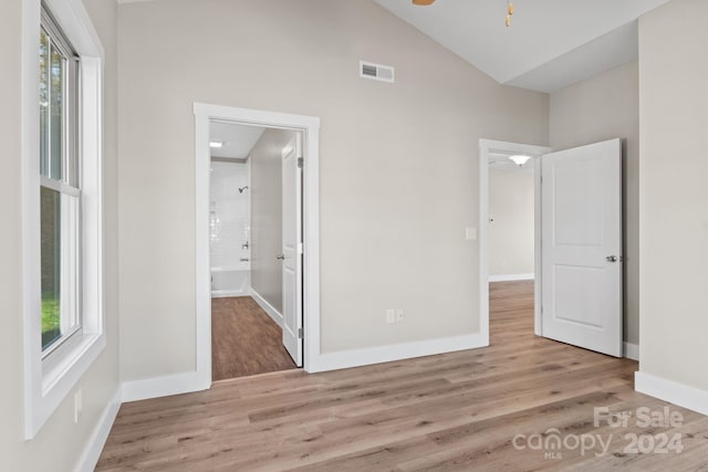 unfurnished bedroom with light wood-type flooring and lofted ceiling