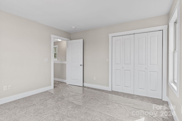 unfurnished bedroom with light colored carpet and a closet