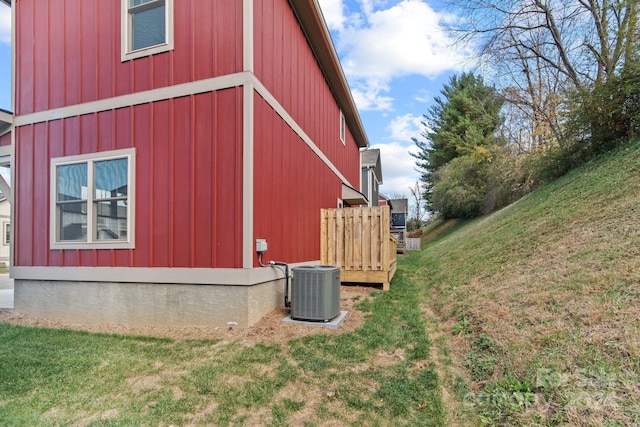 view of side of property with central air condition unit and a lawn