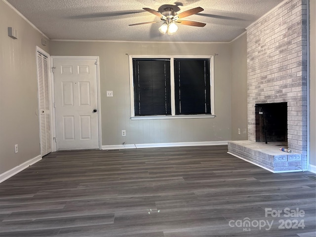 unfurnished living room featuring ceiling fan, a textured ceiling, ornamental molding, dark wood-type flooring, and a fireplace