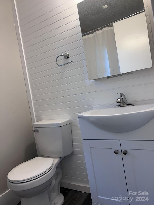 bathroom featuring toilet, wooden walls, wood-type flooring, a shower with shower curtain, and vanity