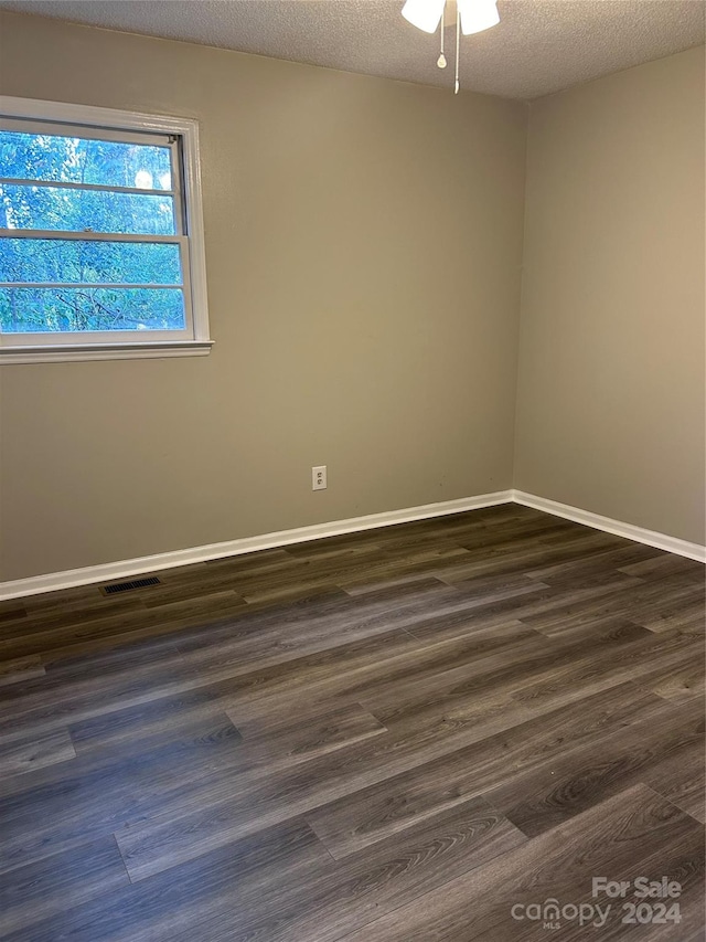 empty room featuring dark wood-type flooring, ceiling fan, and a textured ceiling