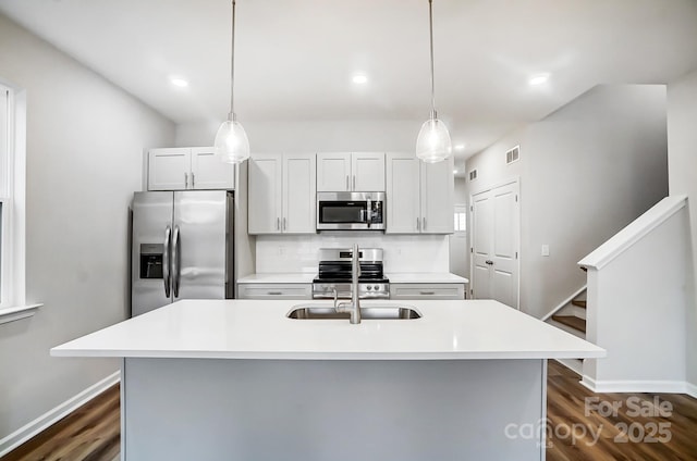 kitchen with white cabinets, appliances with stainless steel finishes, and a kitchen island with sink