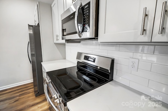 kitchen featuring backsplash, stainless steel appliances, white cabinetry, and hardwood / wood-style flooring