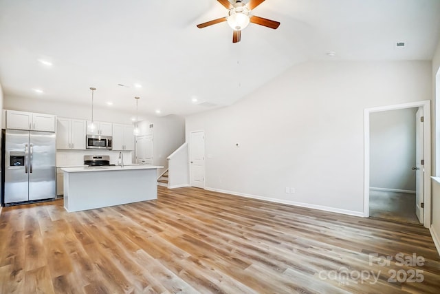 kitchen with stainless steel appliances, pendant lighting, light hardwood / wood-style flooring, white cabinets, and a center island