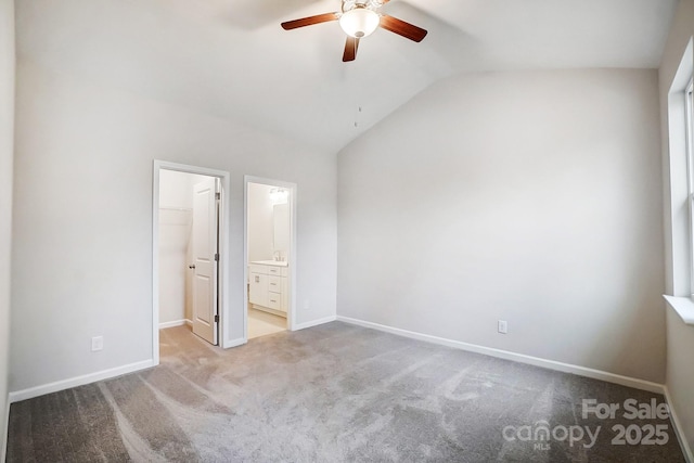 unfurnished bedroom with light carpet, a walk in closet, vaulted ceiling, ceiling fan, and a closet