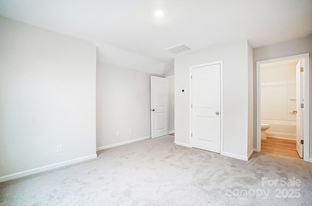 unfurnished bedroom with light colored carpet, connected bathroom, and a closet