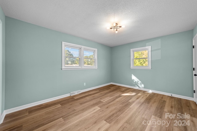 spare room featuring a textured ceiling and light hardwood / wood-style floors