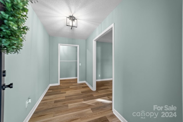 hall with a textured ceiling and hardwood / wood-style floors