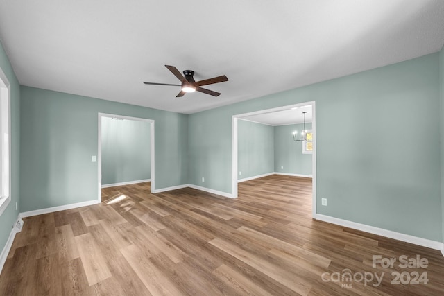 spare room featuring light hardwood / wood-style floors and ceiling fan with notable chandelier