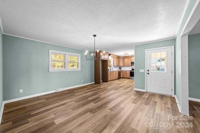 kitchen featuring plenty of natural light, decorative light fixtures, sink, and light wood-type flooring