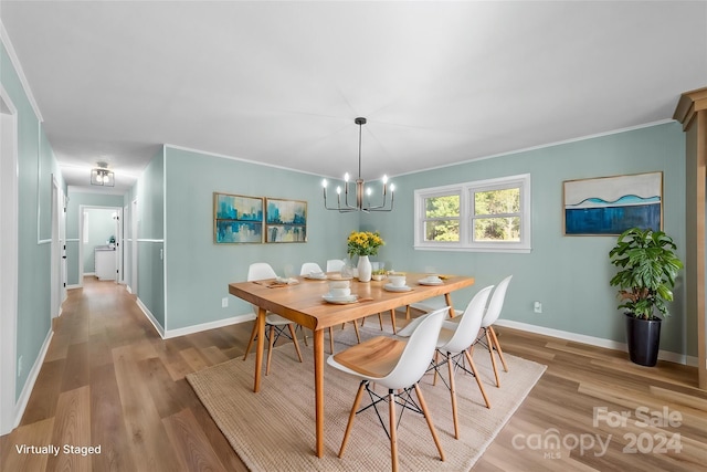 dining space featuring ornamental molding, light hardwood / wood-style flooring, and a notable chandelier