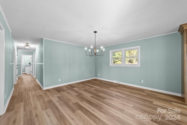 spare room with light hardwood / wood-style floors, a notable chandelier, ornamental molding, and a textured ceiling