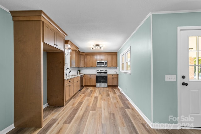 kitchen featuring sink, light hardwood / wood-style floors, stainless steel appliances, crown molding, and decorative backsplash