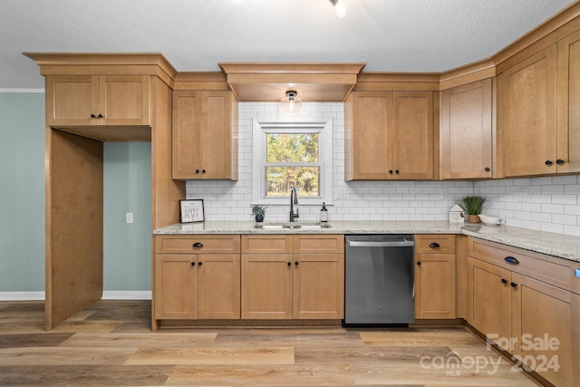 kitchen featuring light stone counters, dishwasher, sink, and light wood-type flooring