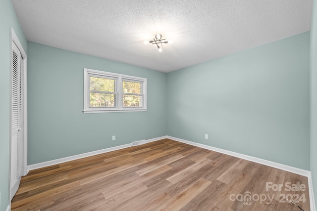 unfurnished bedroom featuring a closet, a textured ceiling, and wood-type flooring