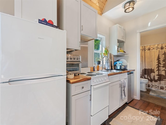 kitchen featuring wooden counters, sink, vaulted ceiling, white cabinets, and white appliances