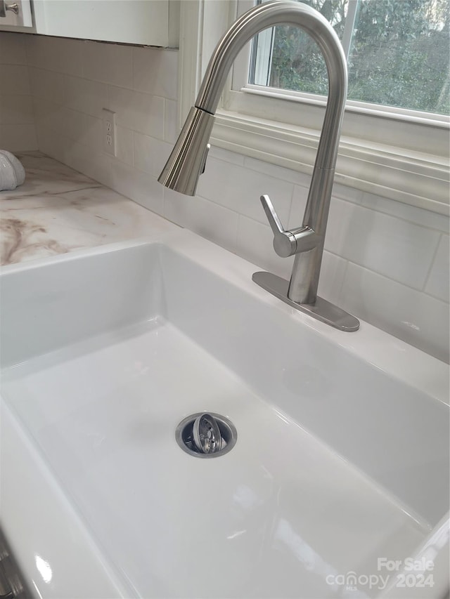 interior details featuring light stone countertops, white cabinets, and sink