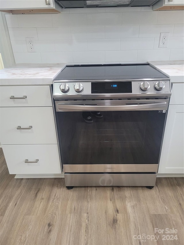 kitchen with light wood-type flooring, white cabinetry, and stainless steel range