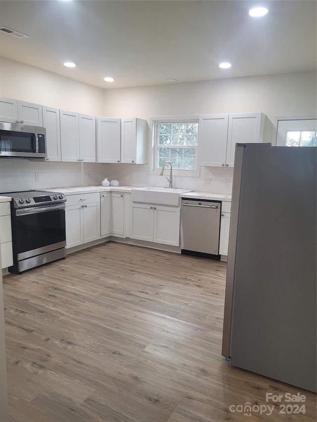 kitchen featuring white cabinets, light wood-type flooring, sink, and appliances with stainless steel finishes