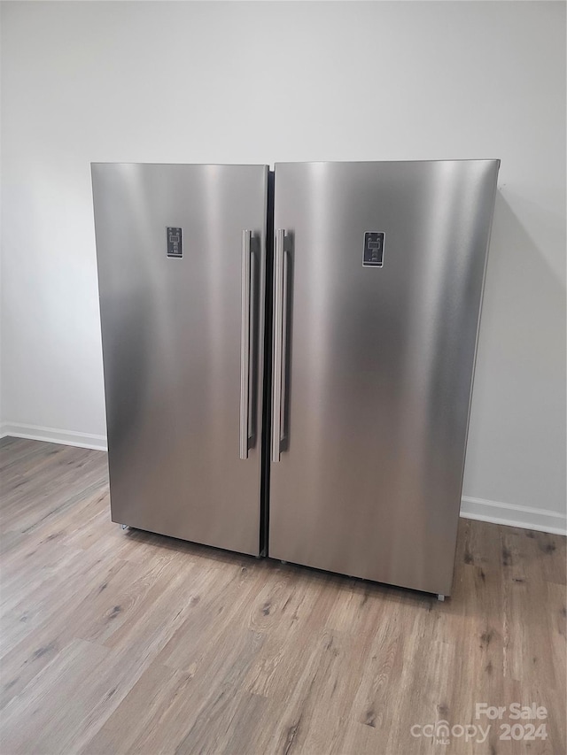 room details featuring stainless steel fridge and light hardwood / wood-style flooring