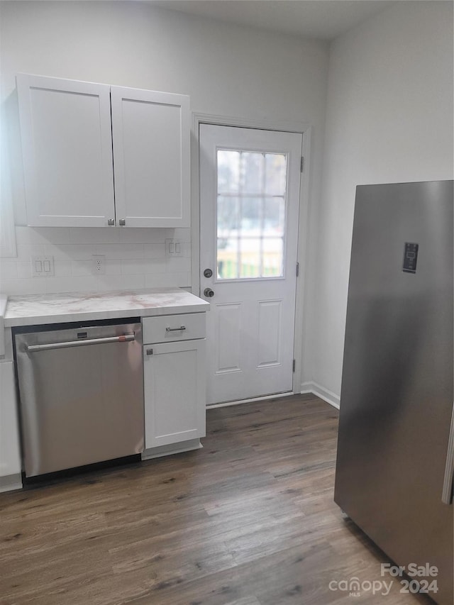 kitchen featuring dark hardwood / wood-style floors, decorative backsplash, white cabinetry, and stainless steel appliances