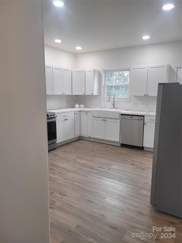 kitchen featuring appliances with stainless steel finishes, light hardwood / wood-style floors, white cabinetry, and sink