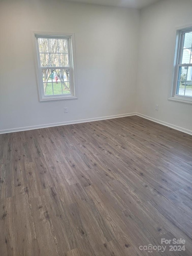 unfurnished room featuring plenty of natural light and dark wood-type flooring