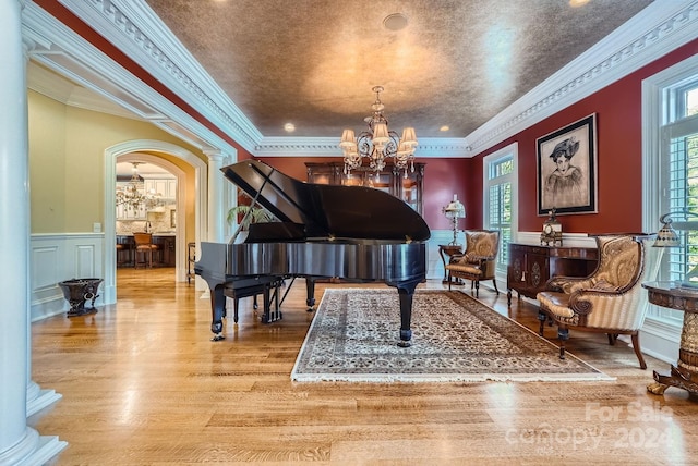 miscellaneous room featuring light hardwood / wood-style floors, crown molding, decorative columns, and a chandelier