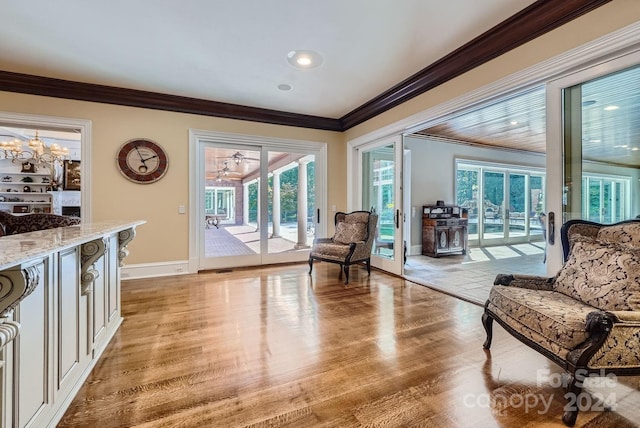 living area with an inviting chandelier, ornamental molding, and light wood-type flooring