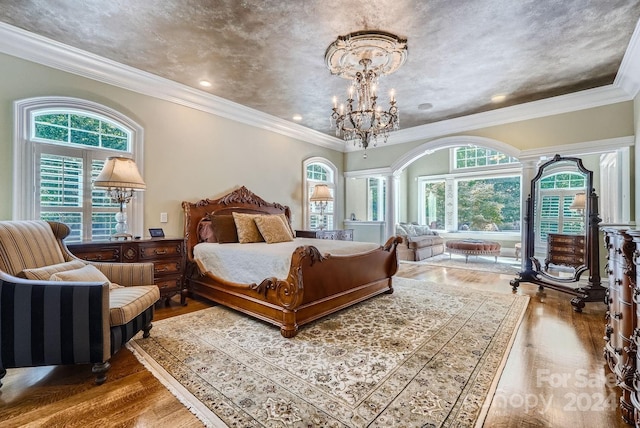 bedroom with ornate columns, crown molding, a chandelier, and hardwood / wood-style floors