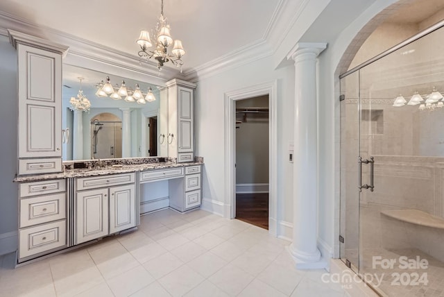 bathroom featuring tile patterned flooring, a shower with shower door, decorative columns, crown molding, and vanity