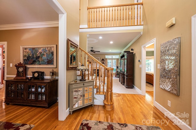 interior space with a towering ceiling, ceiling fan, ornamental molding, and hardwood / wood-style floors