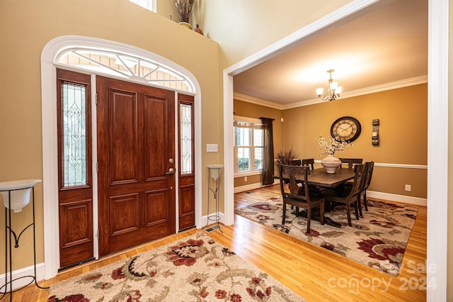 foyer entrance with crown molding, hardwood / wood-style flooring, and a chandelier