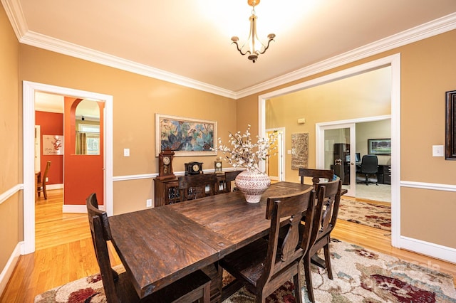 dining area featuring ornamental molding, a chandelier, and light wood-type flooring