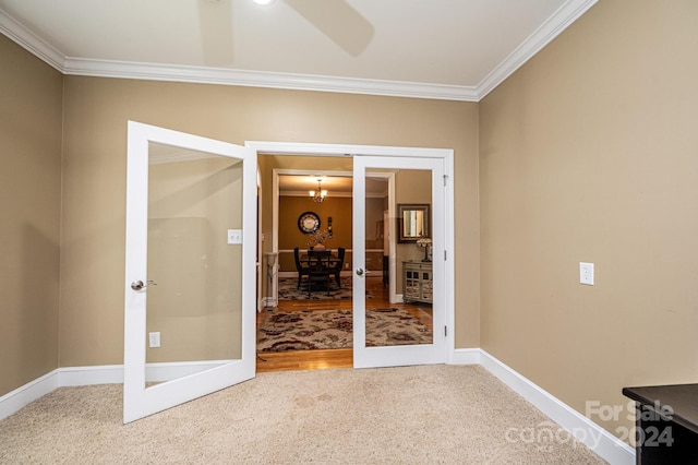 empty room with crown molding, a notable chandelier, and carpet