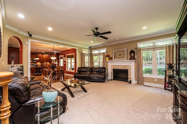 carpeted living room with crown molding, a tiled fireplace, and ceiling fan