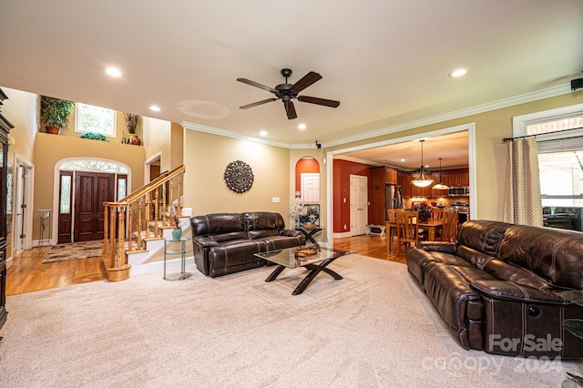 living room featuring crown molding, ceiling fan with notable chandelier, and light hardwood / wood-style floors