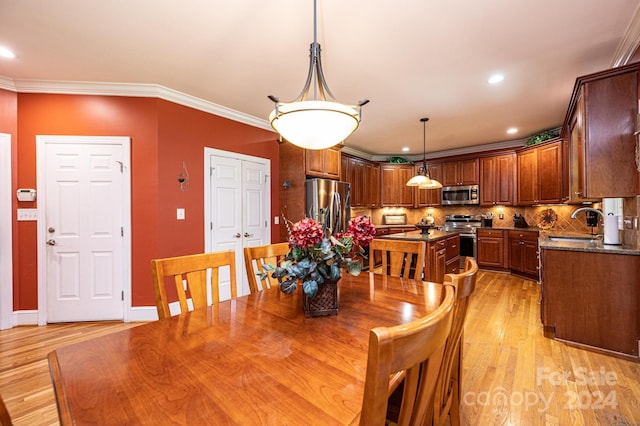 dining room featuring sink, crown molding, and light wood-type flooring