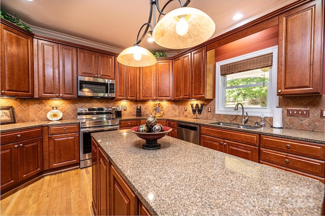 kitchen featuring tasteful backsplash, appliances with stainless steel finishes, sink, pendant lighting, and light hardwood / wood-style flooring