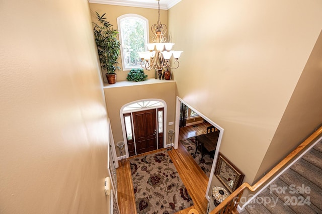 foyer entrance featuring ornamental molding, a notable chandelier, and hardwood / wood-style flooring