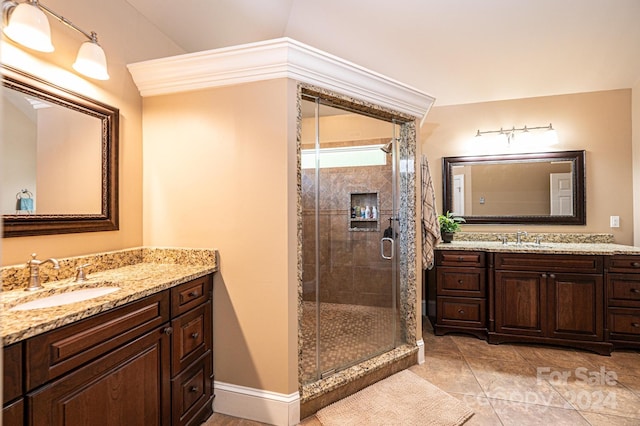 bathroom with a shower with door, vanity, vaulted ceiling, and tile patterned flooring