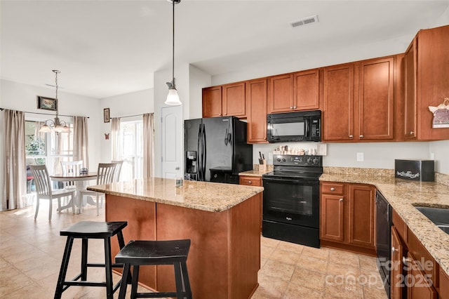 kitchen with a breakfast bar, a center island, black appliances, decorative light fixtures, and a notable chandelier